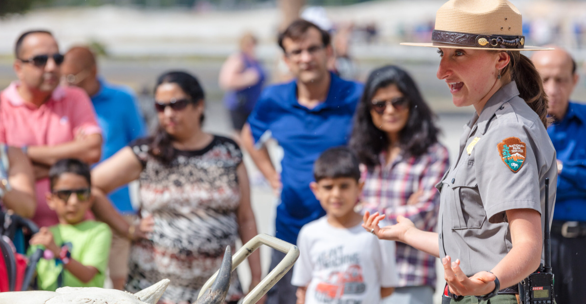 <p>A female ranger talks to a group of people and has a cart with animal skulls on it.</p>
<p>Wildlife safety talk at Old Faithful Visitor Education Center</p>
<ul><li>Keywords: jacob w. frank; old faithful visitor education center; wyoming; yellowstone; yellowstone national park; employees; park rangers; people; recreation; summer</li></ul>