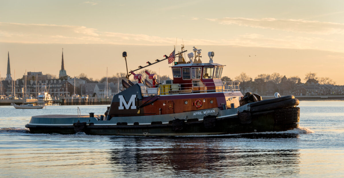 With navigation light mast lowered for bridges tugboat APRIL MORAN - IMO 9373711 heads down the Elizabeth River at dusk off Norfolk Virginia USA on February 2 2017