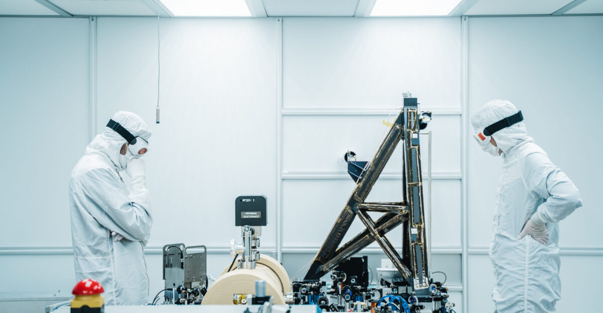 My name is Nutsinee Kijbunchoo and I m a physics PhD student based at the National Australian University Canberra Australia My advisor sent me to LIGO Hanford one of the two U S based gravitational-wave detectors located in the middle of Washington desert to help out with the squeezed light commission and upgrade during the third observing run break it means we stopped listening to black hole and neutron star collisions On a rare day that I didn t have to work at my own corner I followed Georgia Mansell MIT postdoc and Jason Oberling site detector engineer into the Pre-Stabilized Laser PSL enclosure Inside the PSL is where the laser that uses to detect gravitational waves generates It is literally where it all begins The system is capable of outputting 70-80 W of laser power so the room needs to be clean as dust and bugs can cause damage to the coatings While I was watching Georgia and Jason work I snapped this photo as the two were baffled by the low amount of light coupling into the new fiber coupler they just installed Just like all equipment LIGO too needs to be maintained constantly