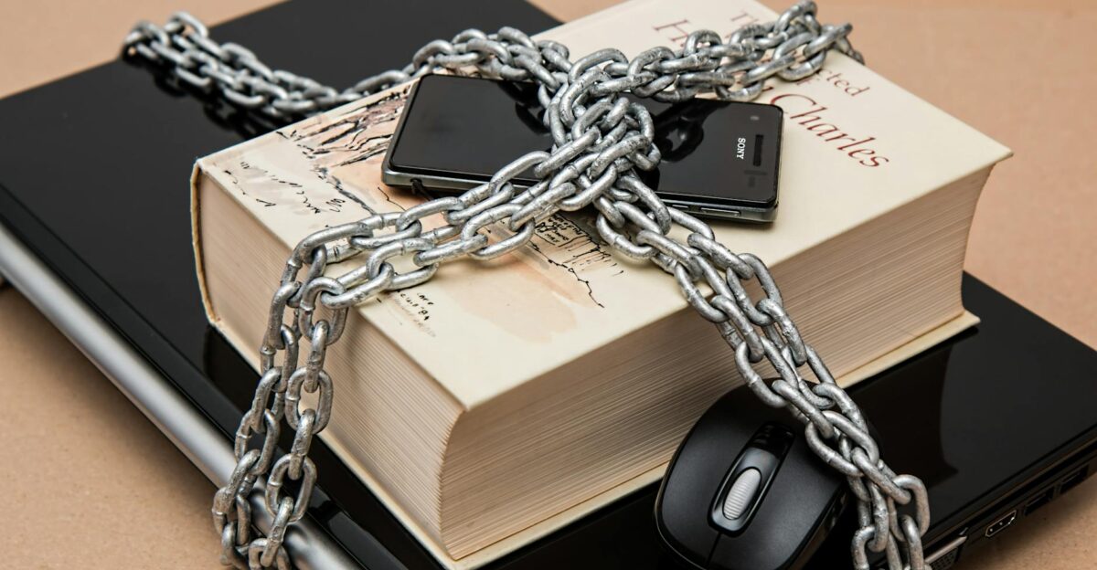Chain-locked book phone and laptop symbolizing digital and intellectual security