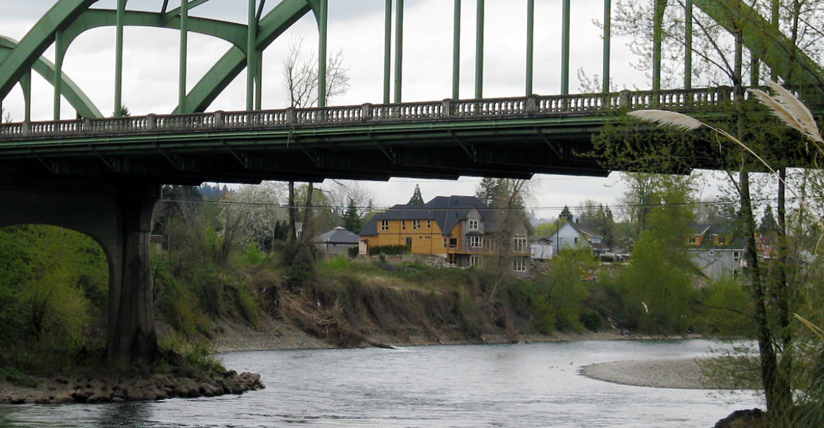Looking upstream on the Clackamas River, 0.2 miles from its confluence with the Willamette River. Oregon Route 99E crosses the bridge. The photo was taken from Clackamette Park in Oregon City. The houses in the background are in Gladstone, Oregon.