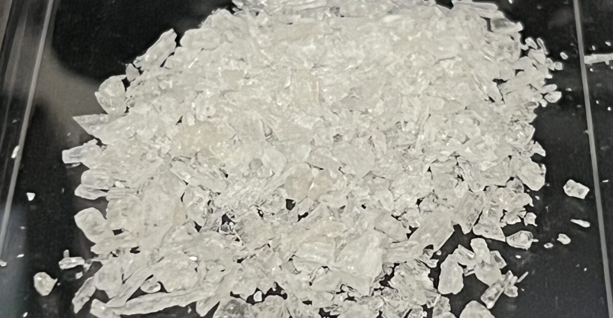 This is a photograph of shards of methamphetamine hydrochloride commonly known as crystal meth in a black background