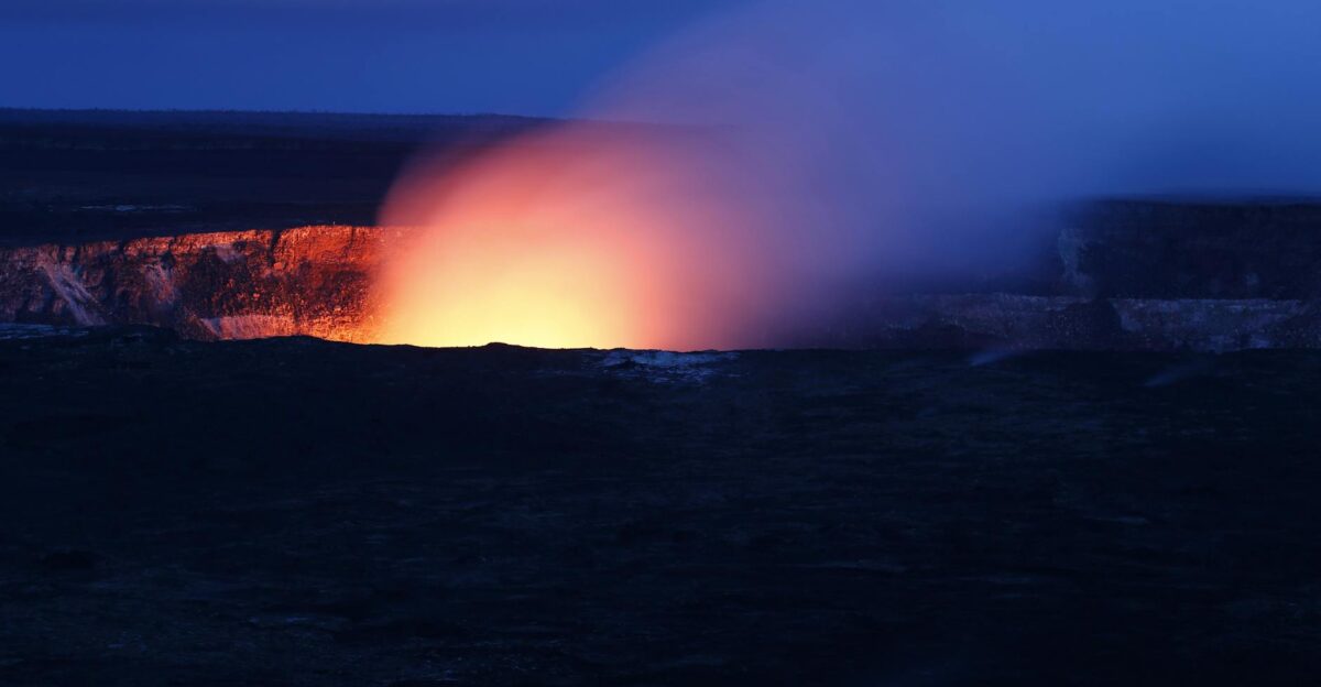 A stunning nighttime view of a volcano eruption with fiery lava glowing against the dark sky
