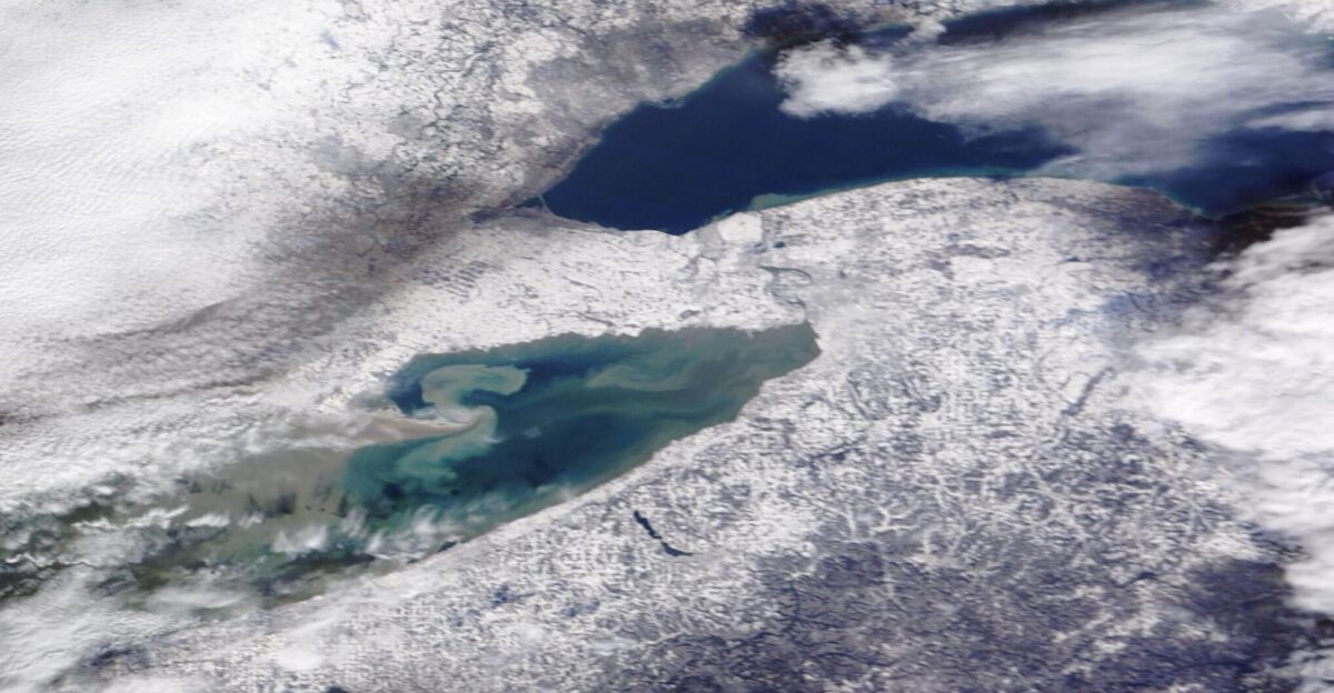 In mid-November 2022 frigid air swept across Lake Erie and Lake Ontario triggering a long-duration lake effect snow event that dropped record snowfall in parts of western New York The first snowflakes fell on November 16 with formation of high-intensity bands of snow following soon after On November 19 the Buffalo Airport reported a record snowfall of 17 2 inches for that date-handily beating the previous record of 7 6 inches which fell on the same date in 2014 By that time Orchard Park south of Buffalo was shivering under a monumental 77 inches of fresh snow The snow came with a price snarling traffic and dropping visibility to less than a half-mile at times Media reported at least two deaths due to the storm and more than 200 people requiring emergency service response or rescue On November 21 as falling flakes began to disappear and the skies to clear the National Weather Service tabulated totals for the storm while residents living in the heaviest bands continued to dig out The town of Hamburg just south of Buffalo won the prize for the deepest snow measuring-in at 81 inches Nearby Orchard Park was next in line with a storm total of 80 inches Meanwhile Tonawanda a northern suburb of Buffalo registered a relatively-sparse 12 1 inches Such wide differences in snow accumulation are common in lake-effect snow due to the formation of snow bands that can be relatively narrow The Moderate Resolution Imaging Spectroradiometer MODIS on board NASA s Terra satellite acquired a true-color image of the aftermath of the snowstorm on November 21 as skies began to clear Clouds remain heavy in the west and over Lake Ontario while sediment swirls in Lake Erie Snow accumulation is heaviest in a ring around Lake Erie especially in the northeast Lake-effect snow occurs along the eastern edge of the Great Lakes when icy wind blows across the lakes from Canada The wind picks up relatively warm moist air over the lakes and pushes it over land where the air is cooler When the moist air encounters cooler temperatures over land the water condenses into precipitation which in cold temperatures falls as snow