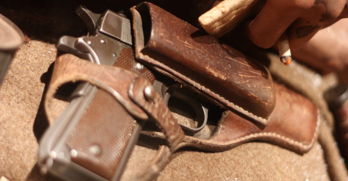 Close-up photo of a collection of misc WW2 militaria historical weapons uniforms military equipment everyday items etc on display at the Baugnez 44 Historical Center a WW2 museum in Baugnez les Malmedy in Belgium focusing on the Battle of the Bulge the Ardennes Counteroffensive from 16 December 1944 to 25 January 1945 and Malmedy massacre on 17 December 1944 Holstered hand gun on mannequin