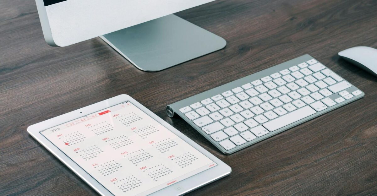 A sleek and modern office desk setup featuring an iMac iPad with calendar keyboard and mouse