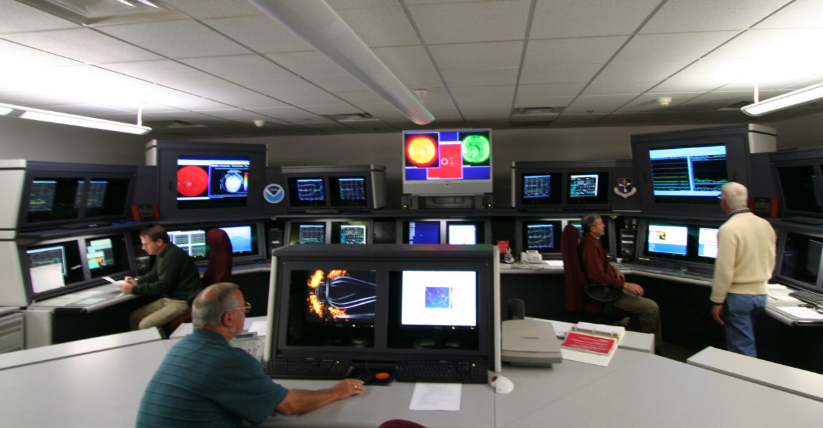 Forecasters in front of lots of screens inside the Space Weather Forecast Office of NOAA's <a href="https://en.wikipedia.org/wiki/Space_Weather_Prediction_Center" class="extiw" title="w:Space Weather Prediction Center">Space Weather Prediction Center</a> (SWPC) in Boulder, Colorado. Scientists keep an eye on the Sun. The GOES satellites send images that show activity on the Sun's surface that means a flare or eruption may be about to happen.