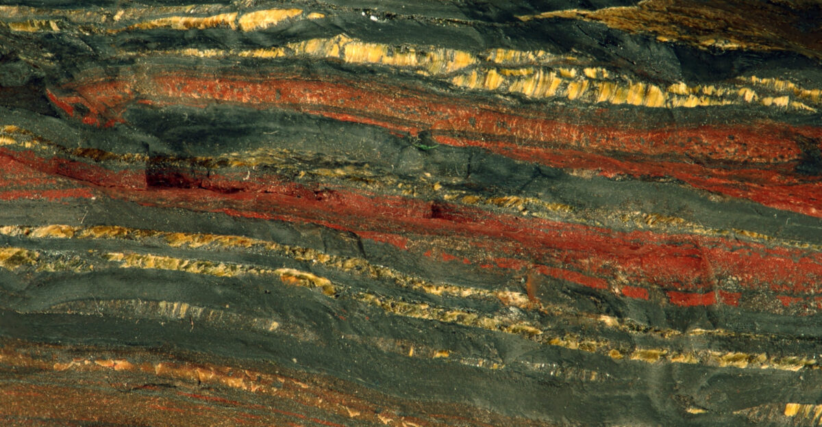 Jaspilite tiger iron from the Precambrian of Australia field of view 4 cm from top to bottom Banded iron formations or BIFs are unusual dense sedimentary rocks consisting of alternating layers of iron-rich oxides and iron-rich silicates Most BIFs are Proterozoic in age although some are Late Archean and do not form today - they re extinct Many specific varieties of iron formation are known and some are given special rock names For example jaspilite is an attractive reddish silvery gray banded rock consisting of hematite red chert jasper and specular hematite or magnetite Because of their age most BIFs have been around long enough to have been subjected to one or more orogenic mountain-building events As such most BIFs are folded and or metamorphosed to varying degrees BIFs are known from around the world but some of the most famous extensive BIF deposits are found in the vicinity of North America s Lake Superior Basin Many BIFs have economic concentrations of iron and are mined BIFs are the most important variety of iron ore on Earth The attractive BIF shown above is from Western Australia s Hamersley Range an area famous for its tiger iron BIFs Several stratigraphic units in the Hamersley Group contain banded iron formation e g the Marra Mamba Fe-Fm the Brockman Fe-Fm The sample here is jaspilite with bands of yellowish-brown tiger-eye asbestiform quartz having chatoyancy The Hamersley Group is an upper Neoarchean to lower Paleoproterozoic unit 2 47 to 2 55 billion years that outcrops in parts of the Hamersley Range Pilbara Craton of Western Australia