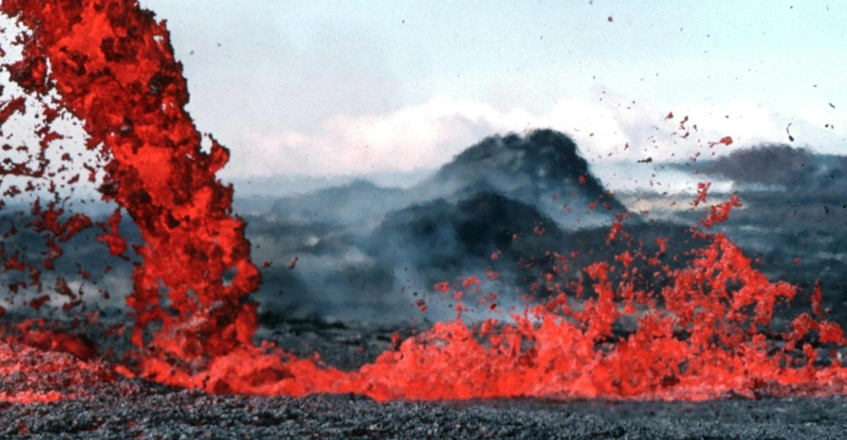 Stunning image of vibrant red lava flowing during a volcanic eruption in a rugged landscape.