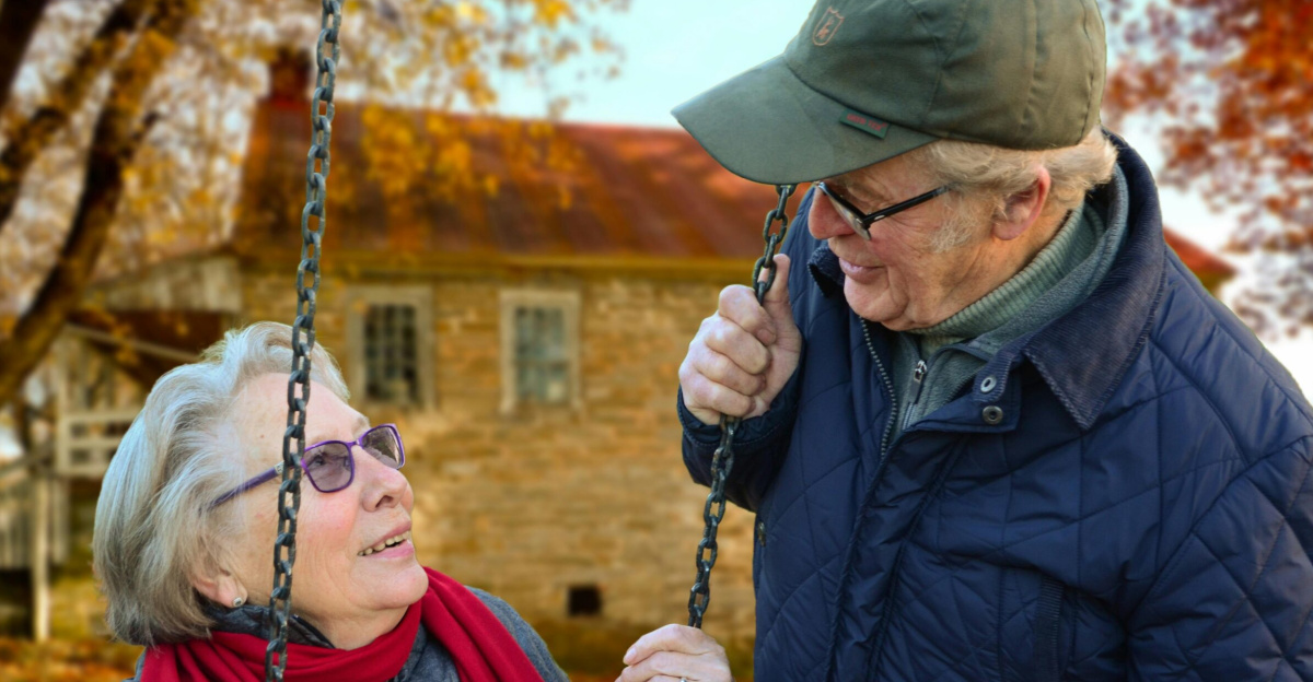 A happy elderly couple sharing a joyful moment on a swing in autumn setting.