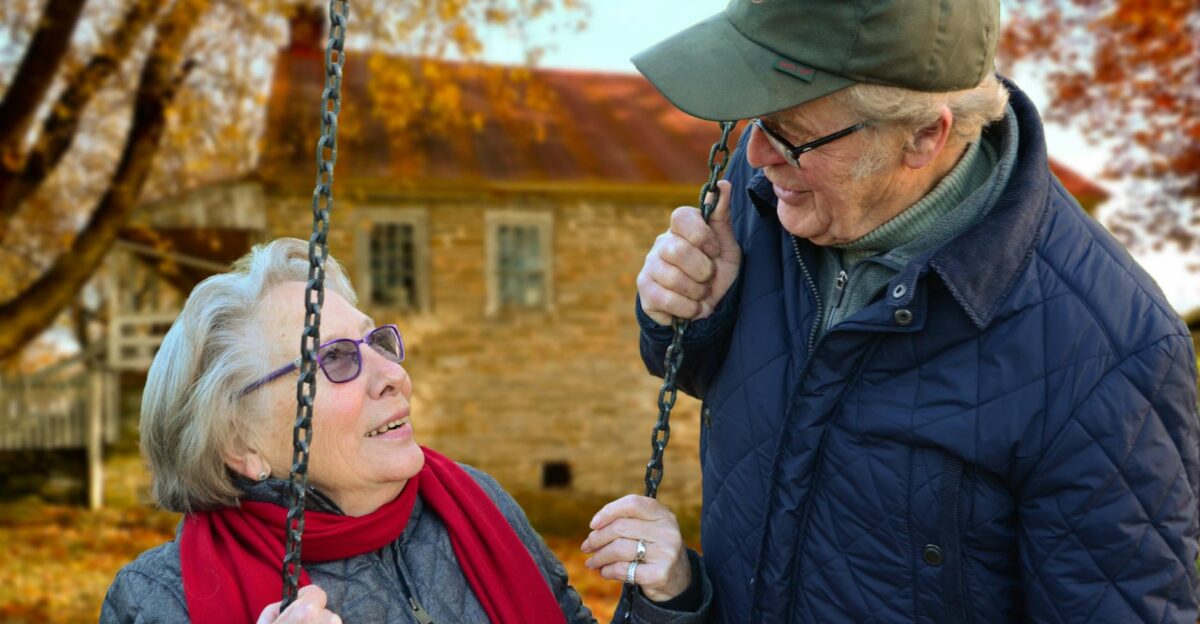 A happy elderly couple sharing a joyful moment on a swing in autumn setting