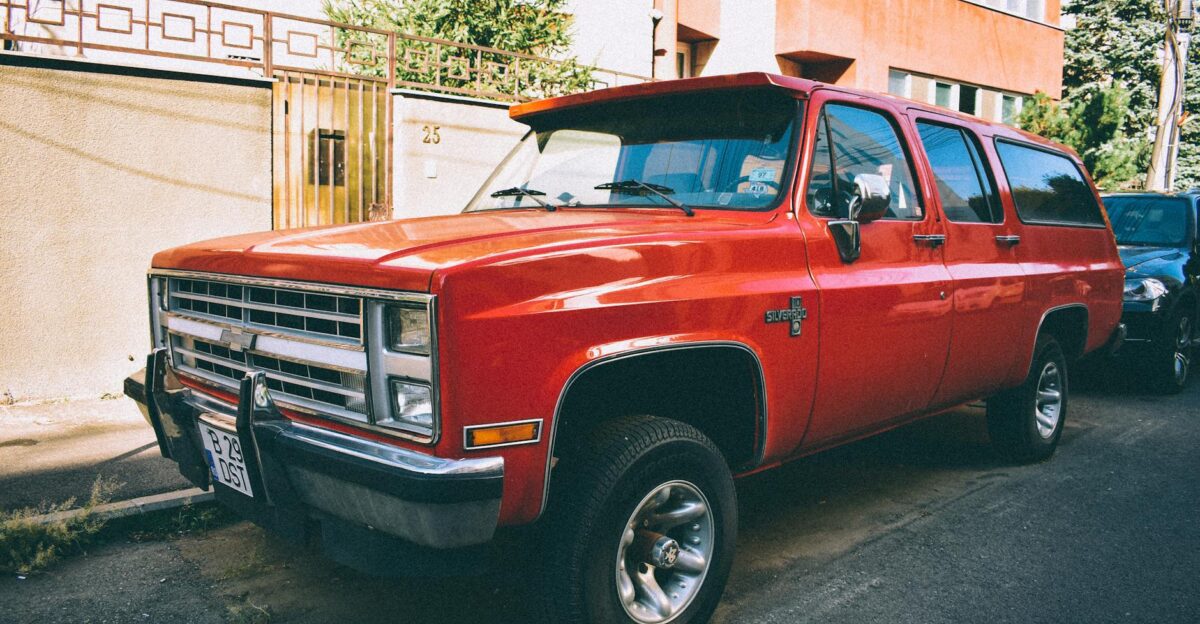 Classic red SUV parked on a sunlit urban street beside buildings