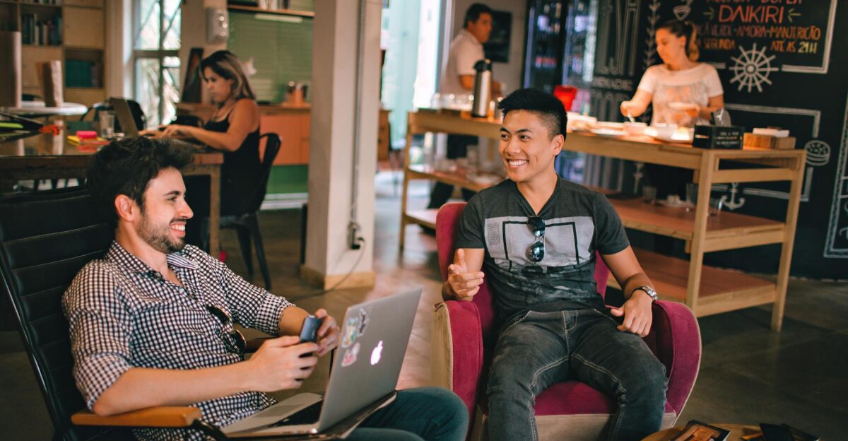 Two men enjoying a relaxed conversation with laptops in a cozy Brazilian caf