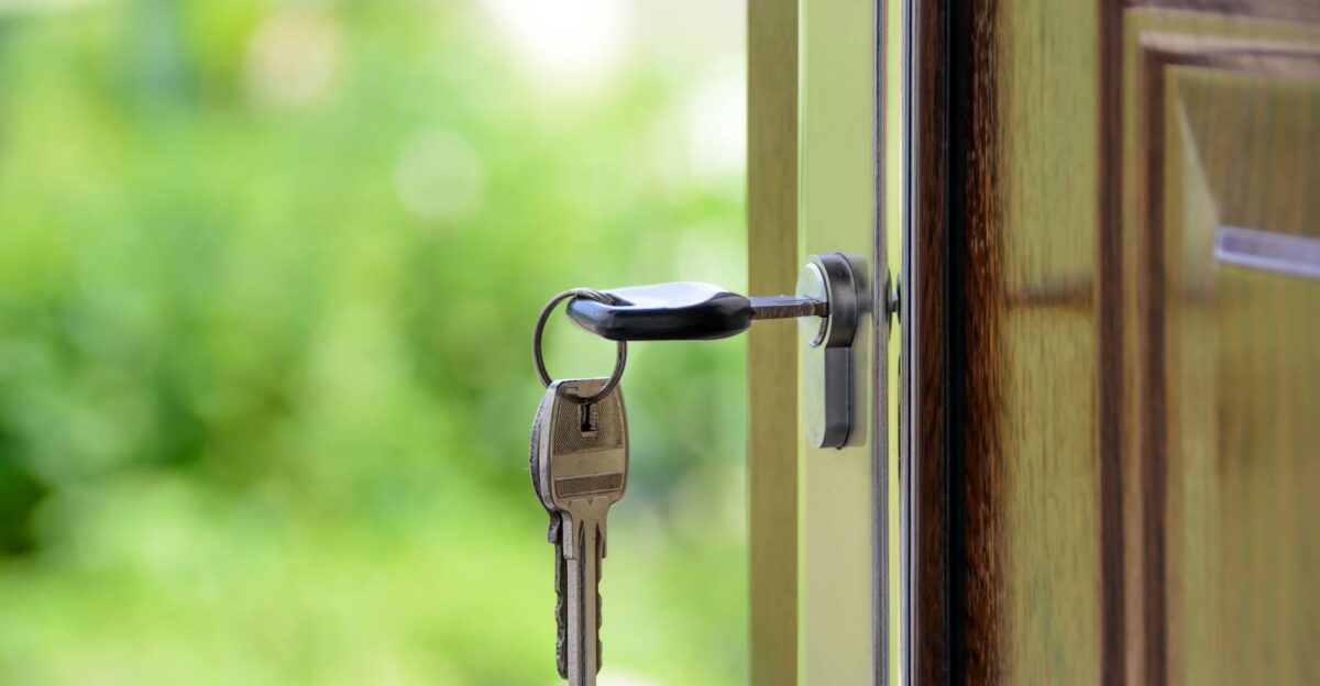 Key inserted in door lock against a blurred green background symbolizing security and real estate