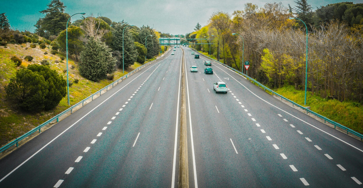Aerial view of an open highway surrounded by trees and clear skies, perfect for travel.