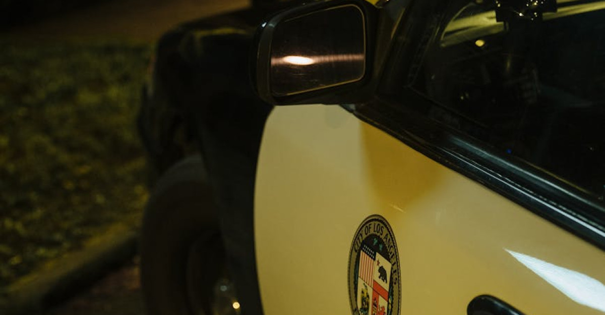 Close-up view of an LAPD car at a nighttime crime scene with yellow tape