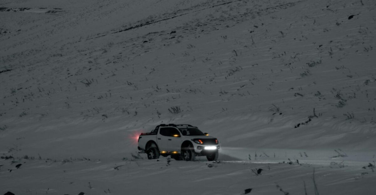Capture of a lone pickup truck navigating a snowy road under a moody winter sky in Kayseri, Türkiye.