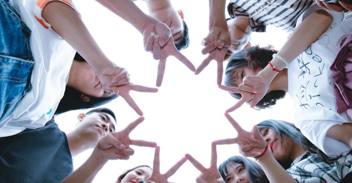 A circle of friends forming a star shape with fingers symbolizing unity and teamwork
