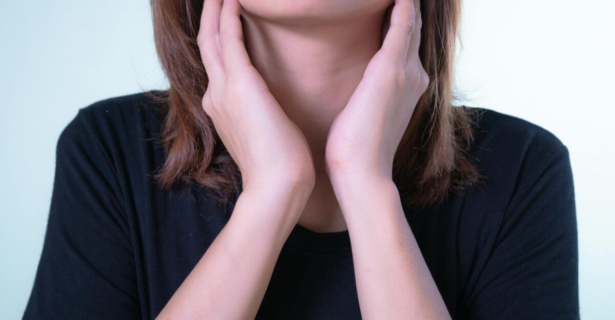 Close-up of a woman touching her neck possibly indicating discomfort or throat pain