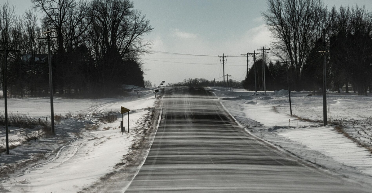 Snow-covered road in Plainview, MN, with bare trees and a winter landscape.