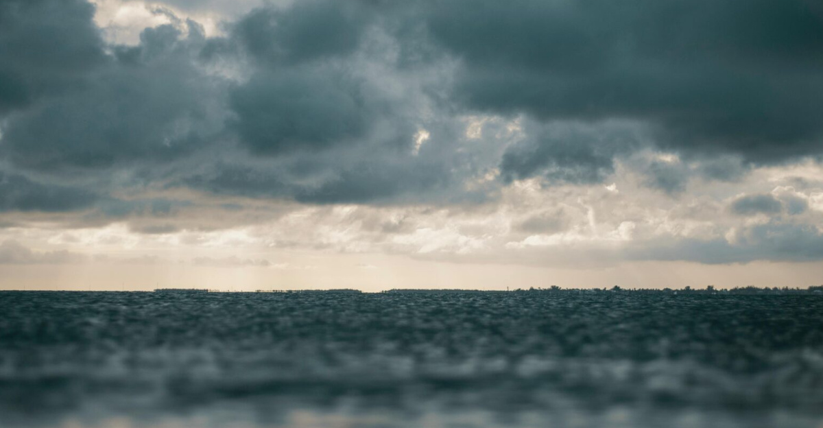A captivating view of the ocean with dramatic dark clouds above, presenting a moody and dramatic seascape.