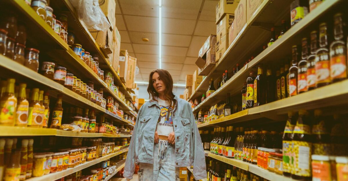 Woman in denim browsing grocery store aisle with products on shelves