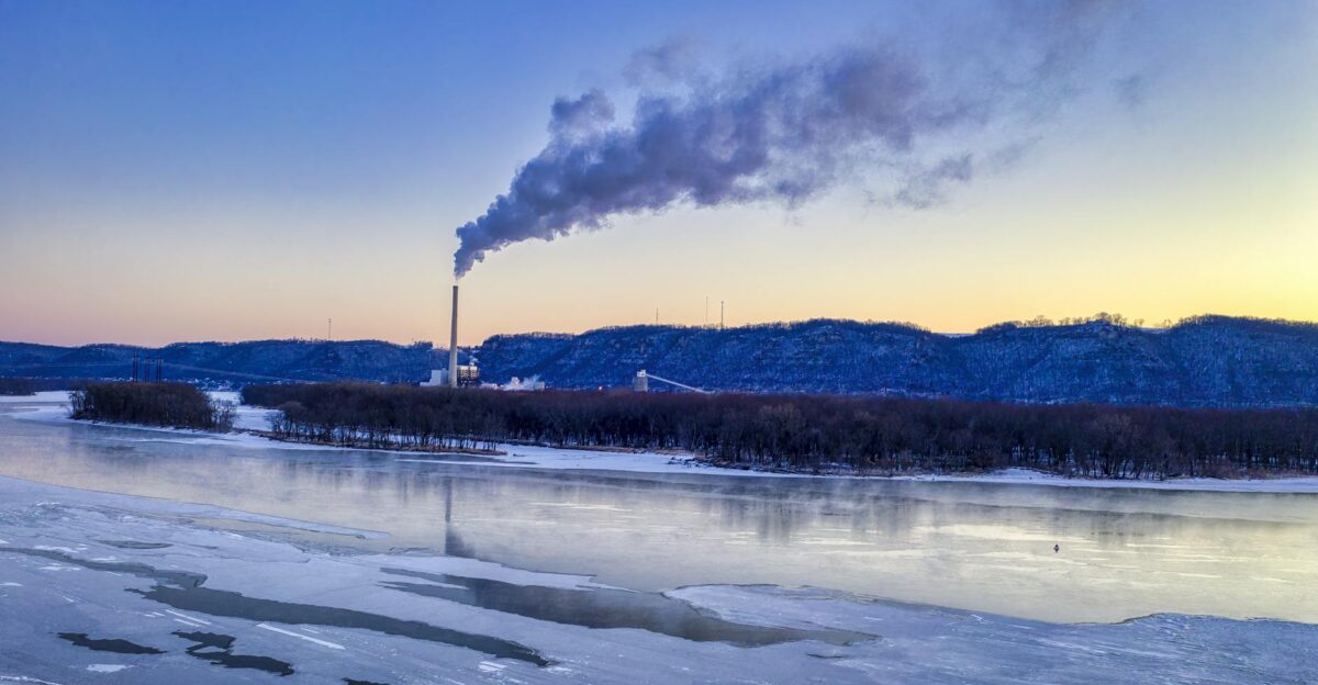 A breathtaking winter landscape with an industrial plant emitting smoke at sunrise in West Newton MN