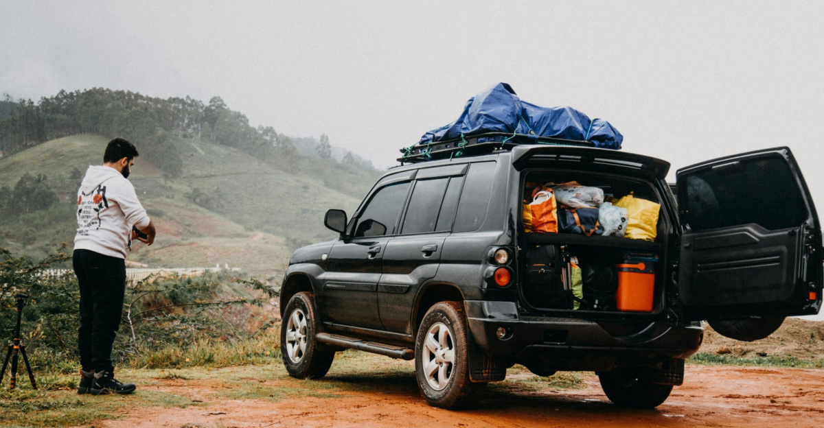 Man prepares for a foggy countryside adventure trip with a packed SUV.