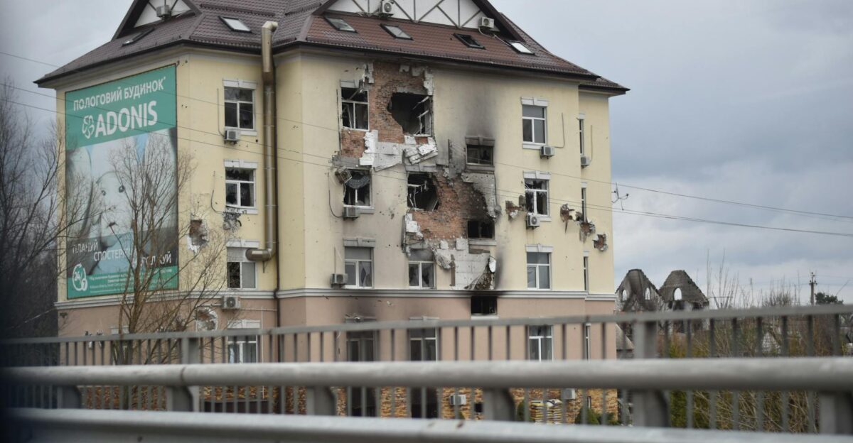 A war-torn residential building showing extensive damage in an urban setting