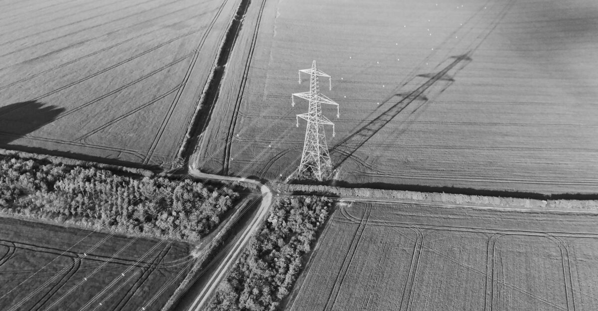 Aerial monochrome image of a power pylon in an English farmland landscape showcasing rural infrastructure