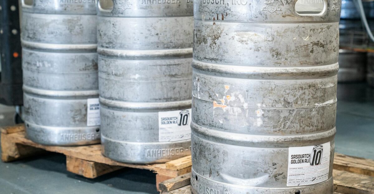Image of metal beer kegs on wooden pallets in an indoor brewery setting ideal for industrial storage themes
