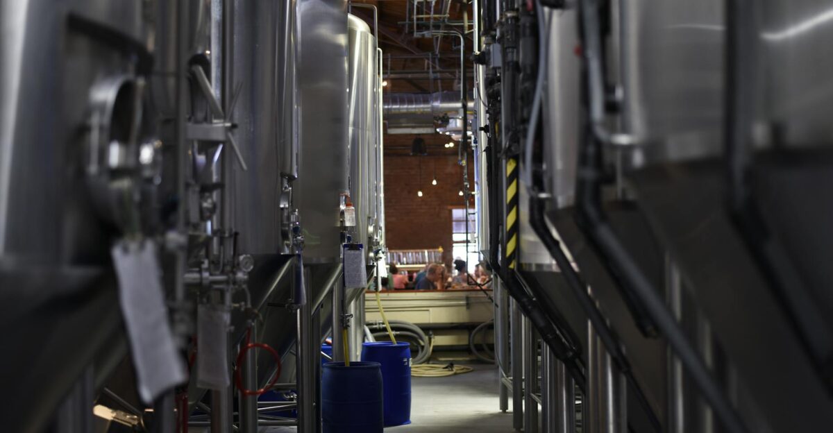 Inside view of a modern brewery with large stainless steel tanks and machinery for beer production