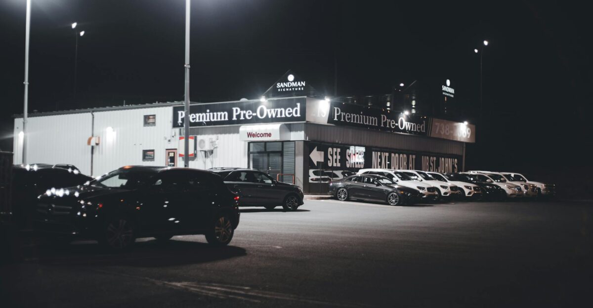 Illuminated car dealership lot showcasing premium pre-owned vehicles at night