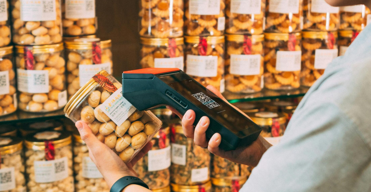 Individual scanning QR codes on jars in a store with a handheld device.