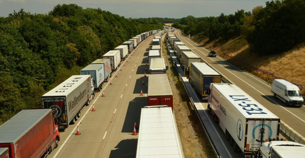 A high-angle shot of trucks and trailers in traffic on a highway in England beneath a bright sky