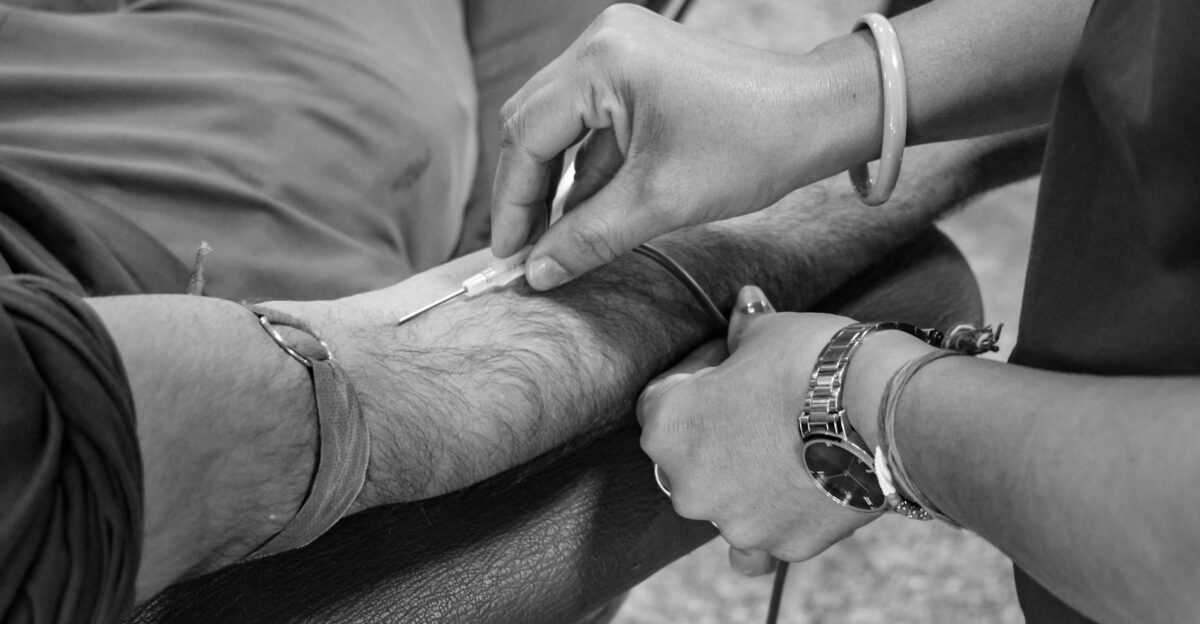 Detailed view of a blood donation procedure in progress focusing on the needle insertion