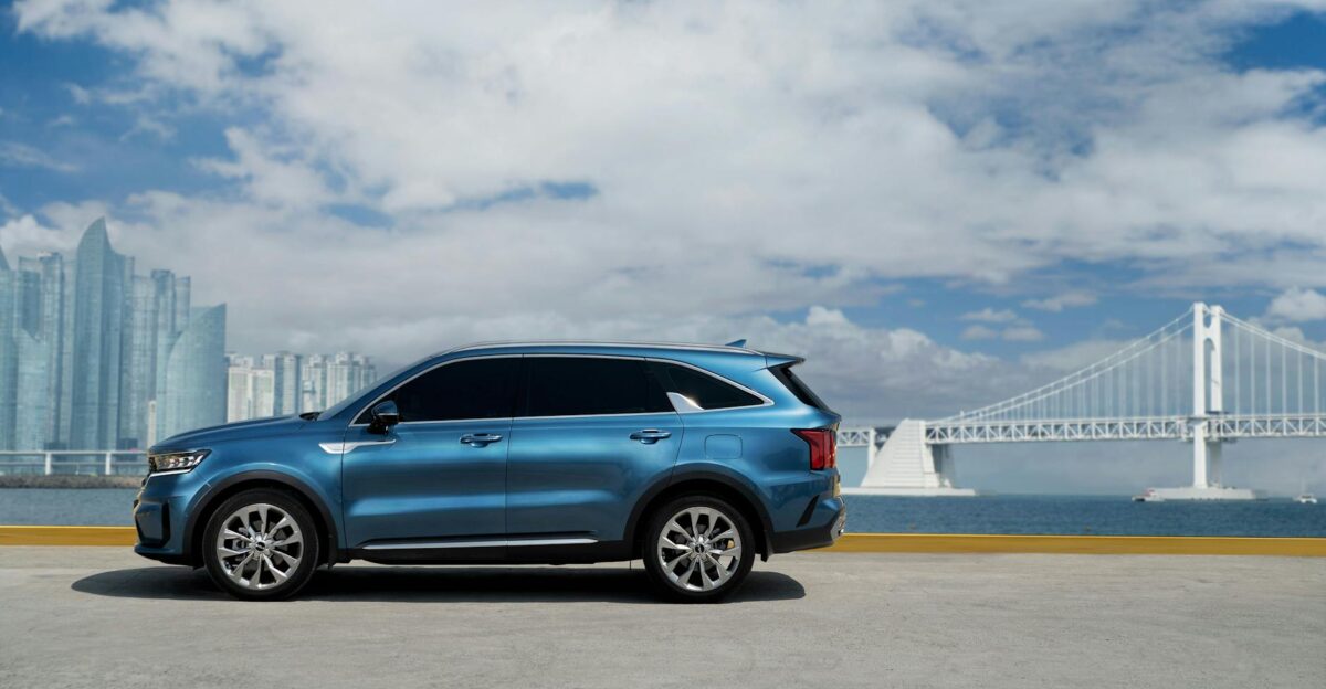 A blue SUV parked near Busan s iconic bridge with a vibrant skyline and ocean view