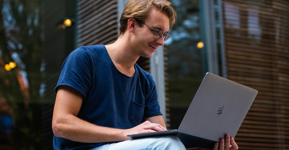 A young man sitting outdoors in Leiden Netherlands working on a laptop
