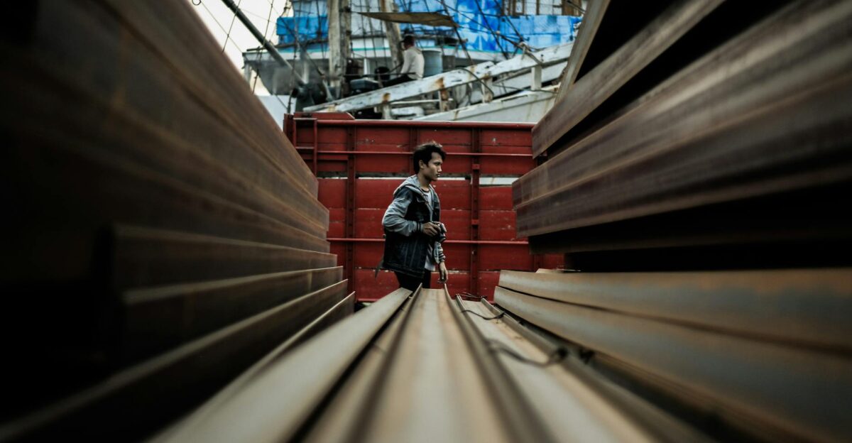 Man walking through an industrial area between steel beams in Jakarta s shipyard