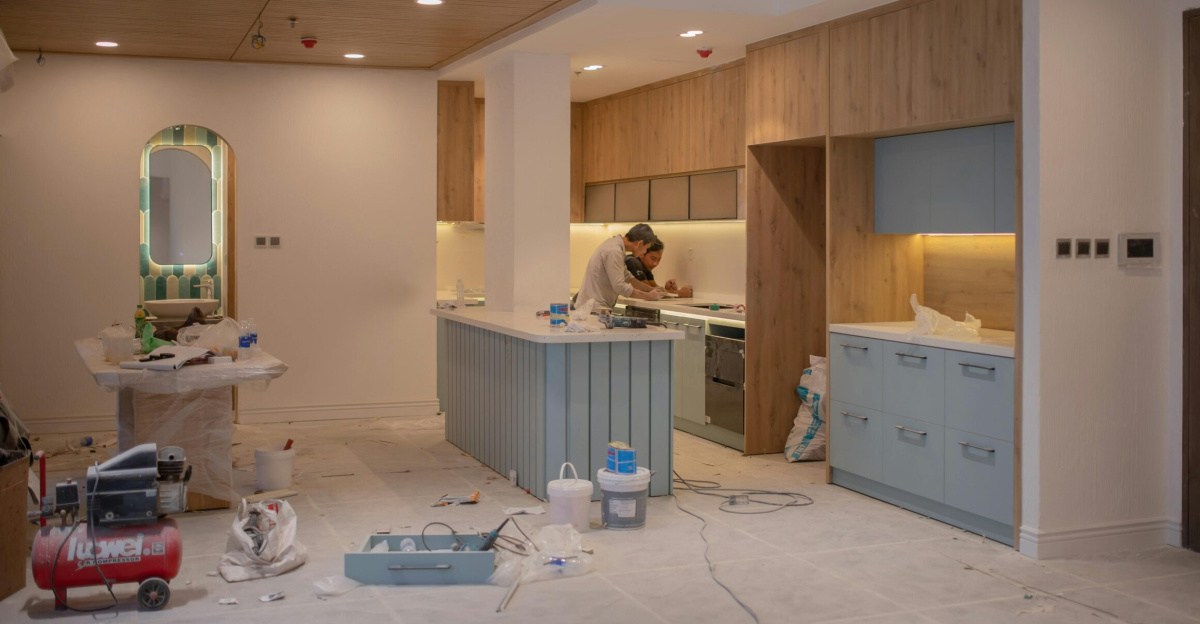 A modern kitchen undergoing renovation, featuring a worker, tools, and materials.