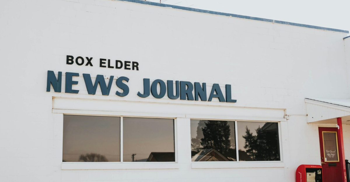 Exterior view of Box Elder News Journal building with red door and sign.