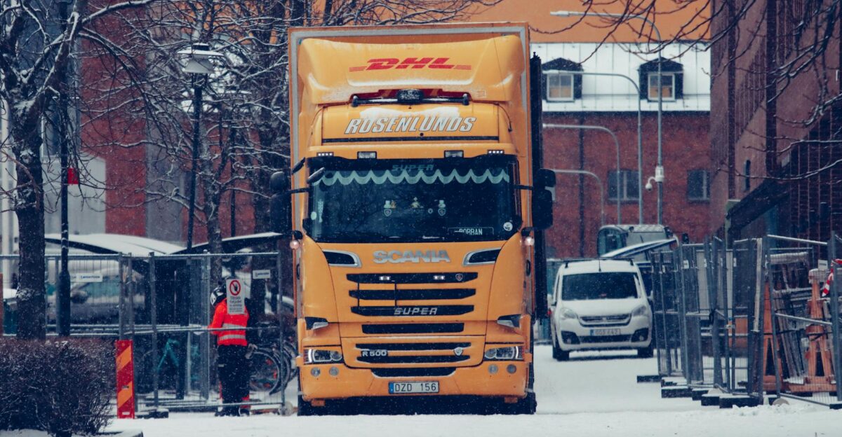 A yellow truck among snowy urban streets surrounded by buildings and winter scenery