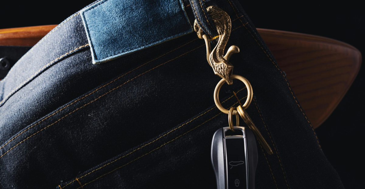 Close-up of denim jeans with a keychain featuring a carved eagle and car key. Stylish accessory detail.