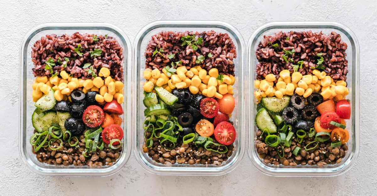 Colorful healthy meal prep with corn olives tomatoes and lentils in glass containers Perfect for mindful eating