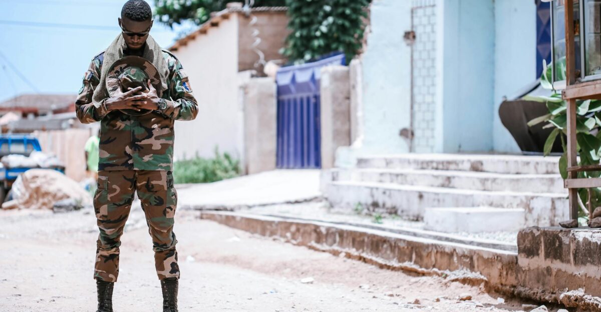 Military soldier in camouflage uniform standing in a sunny urban environment