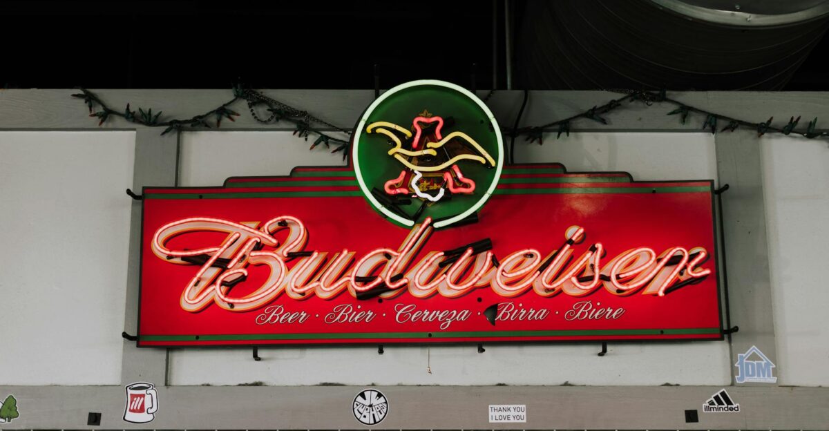 Vibrant neon Budweiser sign with multi-language beer text on an indoor wall setting