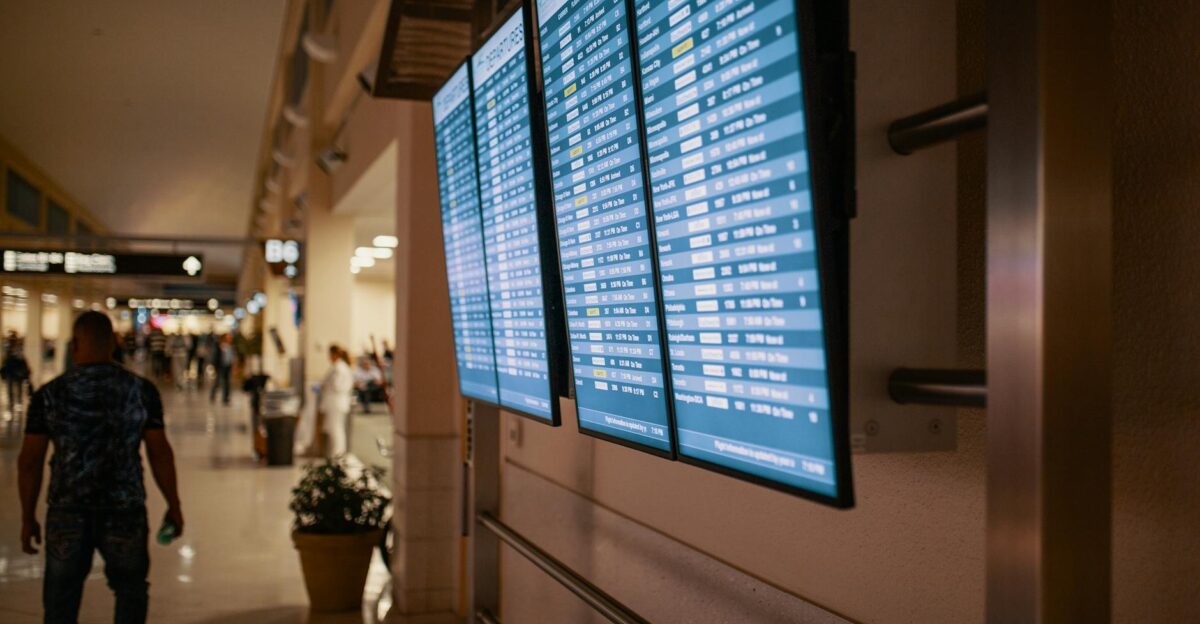 Airport terminal with digital flight information boards showing arrivals and departures