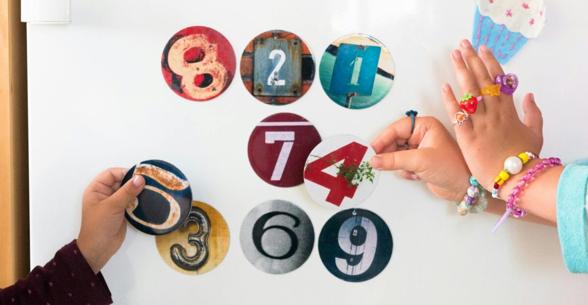 Two children playing with colorful number magnets on a fridge engaging in a fun learning activity