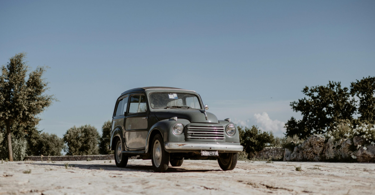 Classic Fiat 500 Topolino parked outdoors in Ostuni, Apulia, Italy under a clear, sunlit sky.