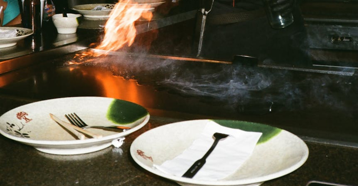 Chef showcasing culinary skills with flames in an open kitchen entertaining diners